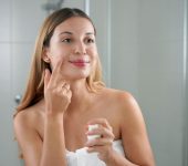 A woman applying anti-aging facial cream with retinol