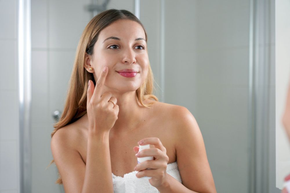 A woman applying anti-aging facial cream with retinol